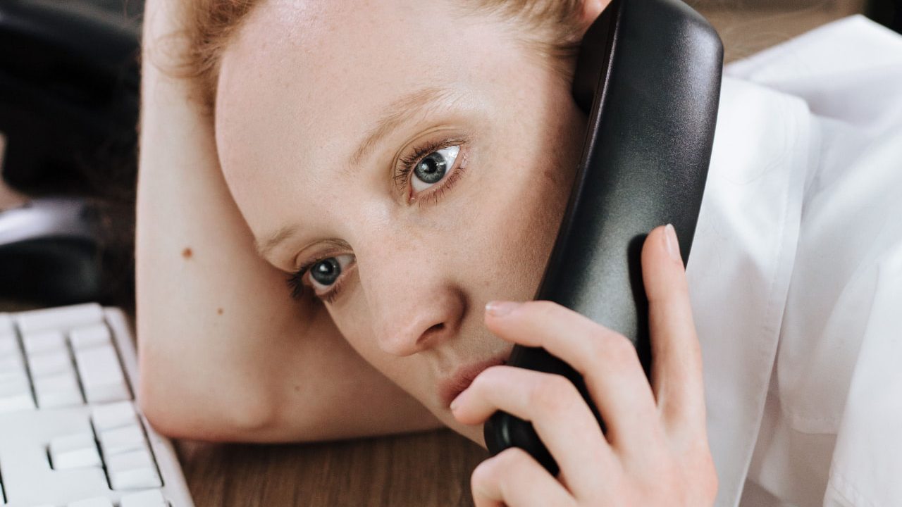 Vermoeide zieke werknemer aan de telefoon die twijfelt of ontslag nemen tijdens ziekte verstandig is
